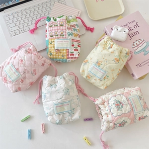 Quilted cotton drawstring camera storage bags in floral and plaid patterns on a desk