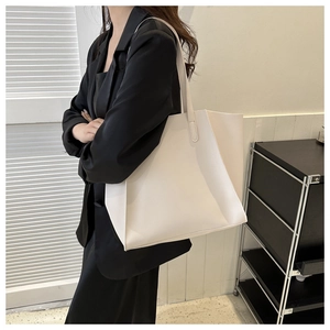 Minimalist white leather tote bag shown on model in a modern office setting