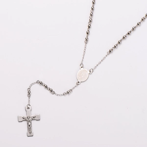 Macro view of stainless steel rosary necklace with cross pendant and Mary medal