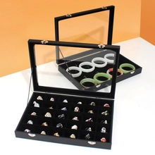Detail showing two black jewelry organizers with clear glass lids for rings and bracelets