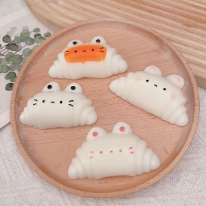 Detailed view of four white cat-shaped croissant squeeze toys on a rustic wooden plate