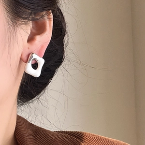 Close-up of minimalist white enamel square hoop earrings on a model for a modern look