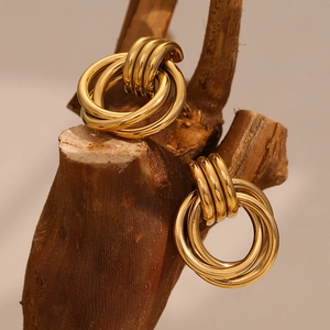 Close-up of layered gold hoop earrings with polished metal finish on a wooden stand