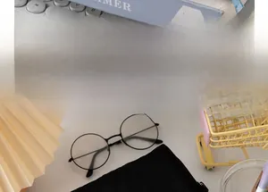 Close-up of retro black round frame glasses on a desk with office accessories