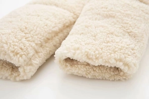 Détail de la texture douce du tissu polaire sherpa blanc crème sur le poignet
