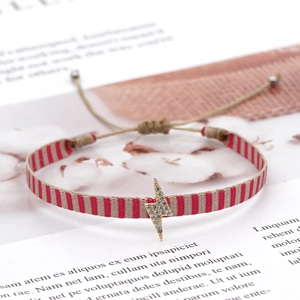 Detail of red and beige woven strap bracelet with micro-pave lightning bolt pendant