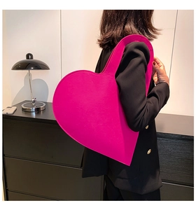 Detailed side view of large bright pink heart-shaped felt tote bag on a model shoulder