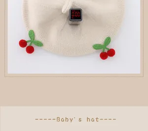 Detail view of apricot baby knit beret showing cherry decor and fluorescent-free testing