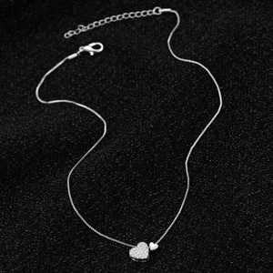 Macro detail of silver double heart pendant with cubic zirconia on a box chain