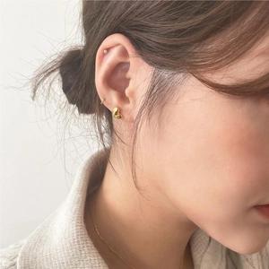 Close-up of golden heart stud earrings on model for delicate minimalist style