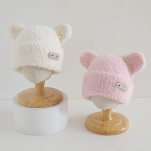 Detail of plush baby hats with bear ears and lace trim in cream and pink colors