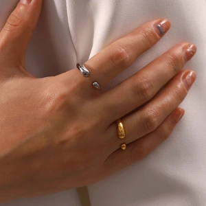 Close-up of gold and silver teardrop open rings in polished titanium steel on model hand