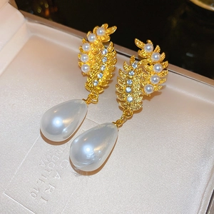 Detail of vintage teardrop pearl earrings with gold leaf design and blue rhinestones