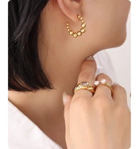 Détail de boucles d'oreilles créoles dorées et bague en zircon portées avec un éclairage doux