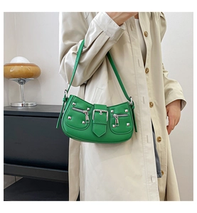 Close-up of green vintage moto-style bag with silver studs and buckles on beige coat