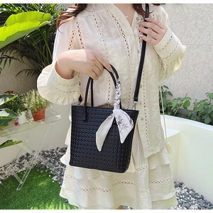 Detail of black woven handbag with silk scarf handle decoration in natural sunlight