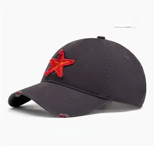 Detail of grey distressed baseball cap with red star patch and frayed brim effects