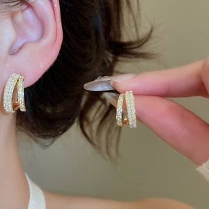 Dettaglio di orecchini a C placcati oro 14k con perle e zirconi sull'orecchio della modella