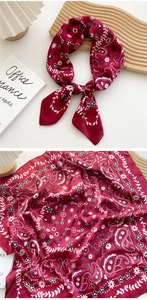 Detail of red floral paisley square scarf on a minimalist wooden tray with warm lighting