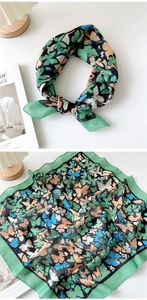 Detail of green floral silk scarf with colorful butterfly print and soft cotton texture