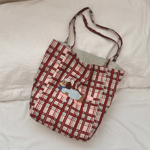 Detail of red and green plaid canvas tote with cute dog embroidery on white fabric