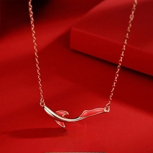 Detailed view of koi fish pendant in rose gold finish with red enamel on a red background
