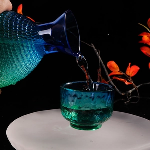 Japanese style hammered peacock blue glass sake set pouring liquid into a cup