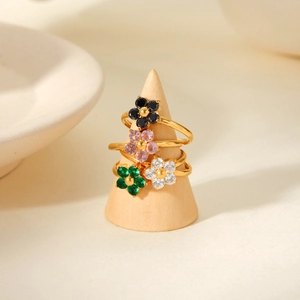 Detail of four gold flower rings with colorful zircon stones on a wood stand