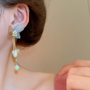 Close-up of butterfly drop earrings with pearls and blue rhinestones on a female model