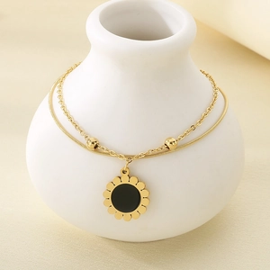 Détail du collier à double rangée avec pendentif tournesol doré sur un vase en céramique