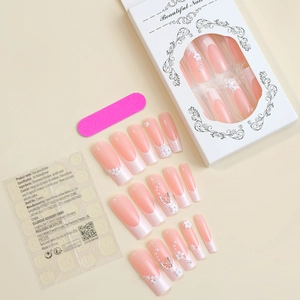 Detail of pink long fake nails with floral and butterfly accents and application kit