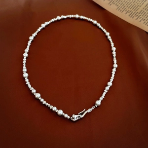 Detailed view of silver beads and white pearls with liquid metal style clasp on necklace
