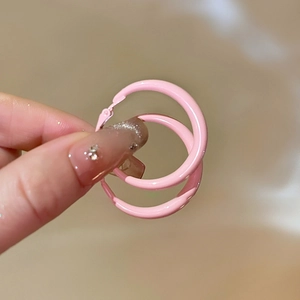 Close-up of a pink smooth enamel round hoop earring held to show glossy finish