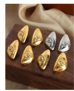 Macro detail of geometric eye-shaped gold and silver earrings with small zircon stone
