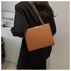 Detail of caramel brown crossbody bag with geometric embossed pattern and gold chain strap