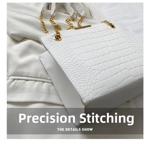 Close-up of white crocodile pattern bag featuring gold chain and neat stitching detail