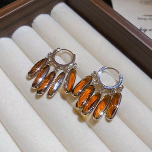 Macro detail of vintage silver tassel earrings with amber crystals in a velvet jewelry box