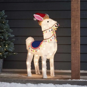 Detailed view of glowing Christmas alpaca light with red hat and blue saddle on wooden deck