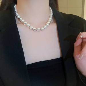 Close-up of double-layer necklace with white pearls and textured silver beads on model