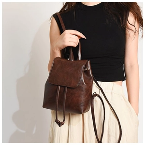 Detail shot of vintage brown PU leather mini backpack with drawstring and flap closure
