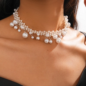 Macro detail of Baroque pearl choker necklace with rhinestone tassel on female model