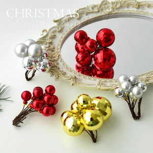 Christmas decorative sprigs with red, gold, and silver balls arranged near an antique mirror