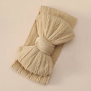 Close-up of beige cable knit baby headband featuring a large bow and soft texture