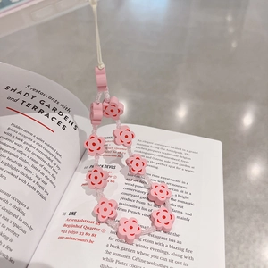 Close-up of pink flower beaded phone strap with resin floral charms on magazine