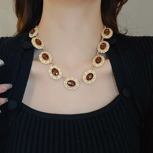 Close-up of vintage gold necklace with brown oval gemstone and diamond accents on a model