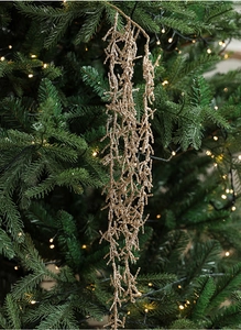 Close-up of champagne gold glitter branch with beads on a decorated Christmas tree