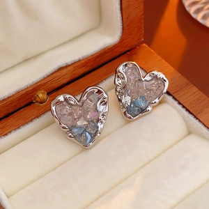 Détail de boucles d'oreilles en cœur avec cristaux bleus sur présentoir en velours