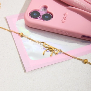 Detailed flat lay of golden bow pendant necklace with heart beads on textured background