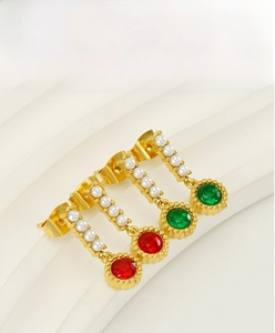 Detailed shot of gold plated oval earrings featuring red and green zircon stones and pearls