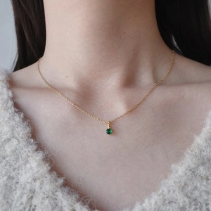 Dettaglio della collana dorata in titanio con ciondolo in pietra portafortuna verde